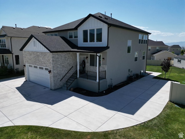 1573 N Woodside Dr, Spanish Fork, UT 84660 - modern farmhouse with stone siding, a porch, concrete driveway, a front yard, and roof with shingles