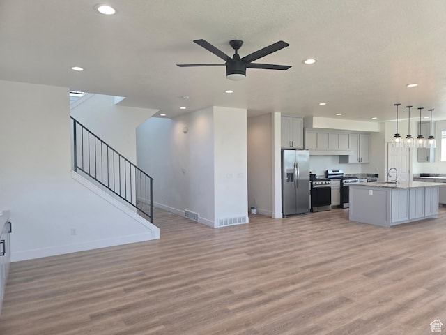 1573 N Woodside Dr, Spanish Fork, UT 84660 - unfurnished living room with light wood-style floors, recessed lighting, a ceiling fan, baseboards, and stairway