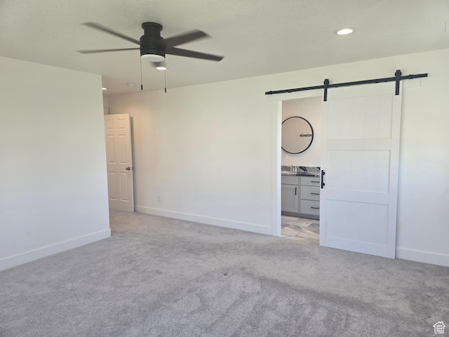 1573 N Woodside Dr, Spanish Fork, UT 84660 - unfurnished bedroom with a barn door, baseboards, light colored carpet, ensuite bathroom, and recessed lighting