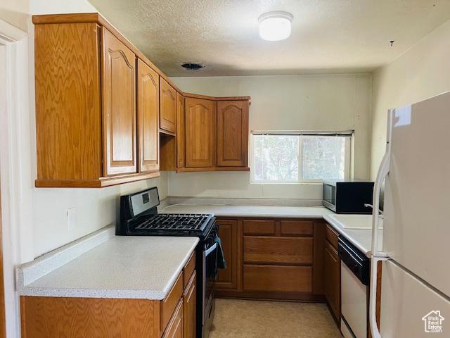 4562 S 785 E, Millcreek, UT 84107 - kitchen with freestanding refrigerator, gas stove, dishwashing machine, and brown cabinetry
