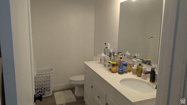 3065 S Brinker Ave, Ogden, UT 84403 - bathroom featuring toilet, vanity, wood finished floors, and baseboards