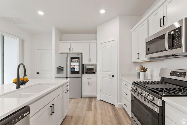 6134 S Kelly Ln, St George, UT 84790 - kitchen with appliances with stainless steel finishes, a sink, white cabinetry, light wood-style flooring, and recessed lighting