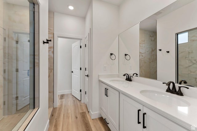 6134 S Kelly Ln, St George, UT 84790 - full bathroom with double vanity, wood finished floors, a tile shower, recessed lighting, and baseboards