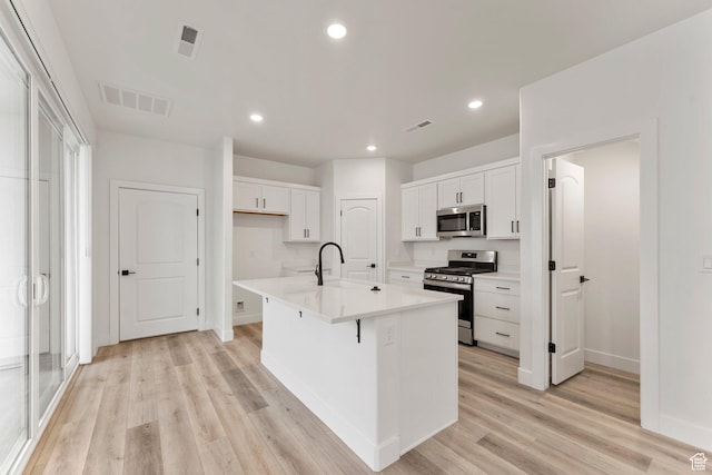 6134 S Kelly Ln, St George, UT 84790 - kitchen with stainless steel appliances, a sink, white cabinetry, light wood-style flooring, and recessed lighting