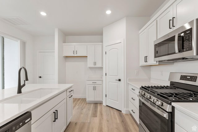 6134 S Kelly Ln, St George, UT 84790 - kitchen with appliances with stainless steel finishes, a sink, light wood-style floors, white cabinets, and light countertops