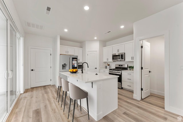 6134 S Kelly Ln, St George, UT 84790 - kitchen featuring appliances with stainless steel finishes, a sink, a breakfast bar, light wood-type flooring, and white cabinets
