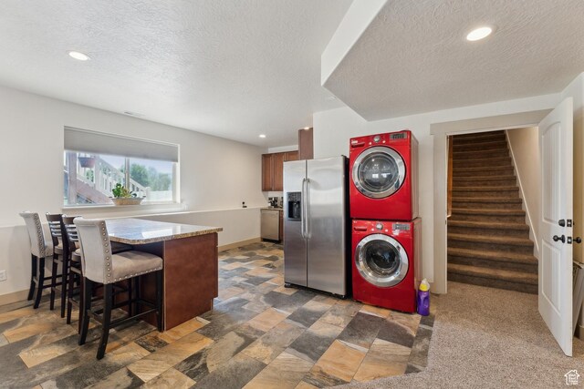 261 W 1200 S, Lehi, UT 84043 - laundry area with stacked washer and clothes dryer, a textured ceiling, recessed lighting, baseboards, and light stone finish flooring