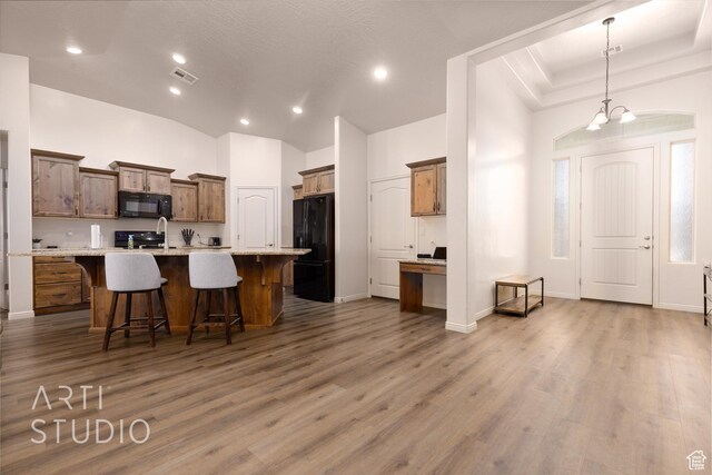 3504 E 3140 S, St George, UT 84790 - kitchen with black appliances, wood finished floors, a breakfast bar area, a center island with sink, and light countertops