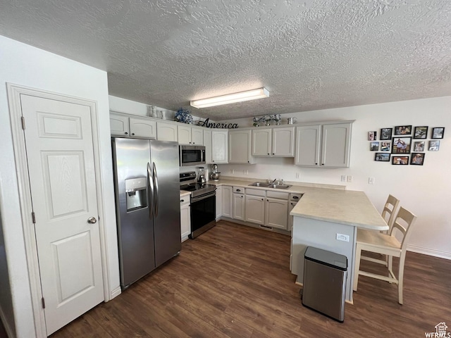 1305 S 1410 E, Provo, UT 84606 - kitchen featuring appliances with stainless steel finishes, a peninsula, a sink, a kitchen bar, and a textured ceiling