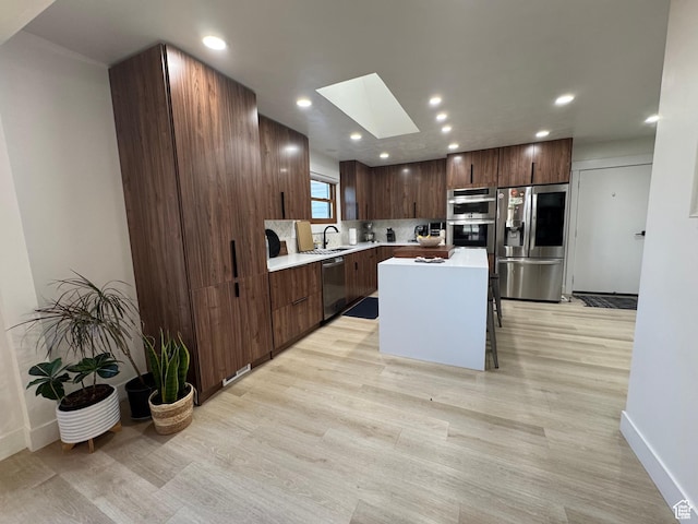 4288 S Shirley Ln, Holladay, UT 84124 - kitchen with appliances with stainless steel finishes, a skylight, light countertops, light wood-style flooring, and recessed lighting