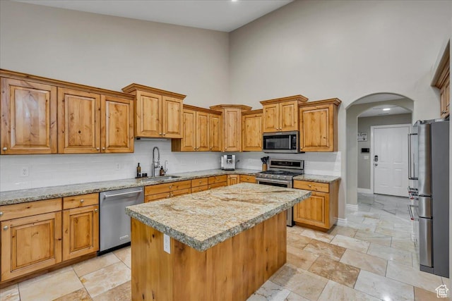 10605 S Willow Valley Rd W, South Jordan, UT 84095 - kitchen with stainless steel appliances, a sink, a high ceiling, backsplash, and arched walkways