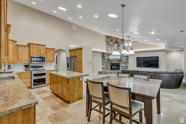 10605 S Willow Valley Rd W, South Jordan, UT 84095 - kitchen featuring appliances with stainless steel finishes, a stone fireplace, open floor plan, backsplash, and a sink
