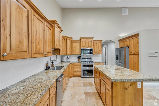 10605 S Willow Valley Rd W, South Jordan, UT 84095 - kitchen featuring stainless steel appliances, a towering ceiling, backsplash, a center island, and arched walkways
