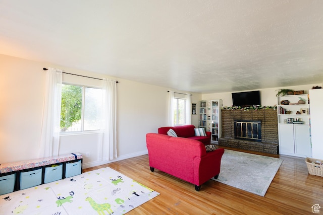 374 W Melba Dr S, Tooele, UT 84074 - living area with wood finished floors, plenty of natural light, a brick fireplace, and baseboards