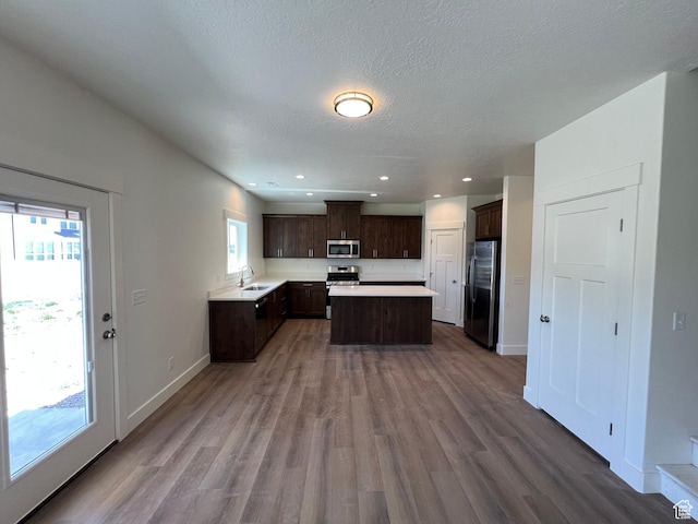 1154 E 1150 S, Garland, UT 84312 - kitchen featuring appliances with stainless steel finishes, a sink, dark brown cabinetry, light countertops, and wood finished floors