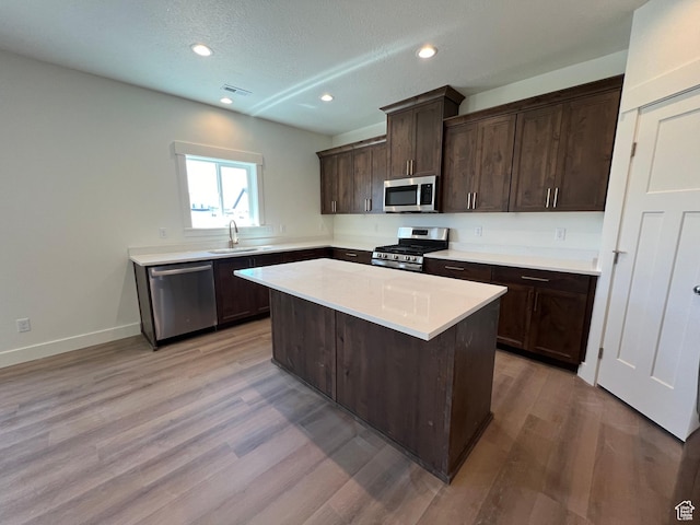 1154 E 1150 S, Garland, UT 84312 - kitchen with stainless steel appliances, dark brown cabinetry, light wood finished floors, a center island, and light countertops