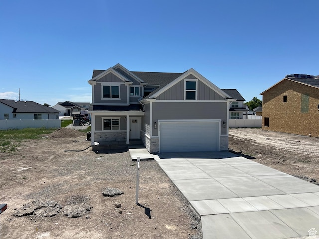 1154 E 1150 S, Garland, UT 84312 - view of front of house featuring board and batten siding, stone siding, a garage, and concrete driveway