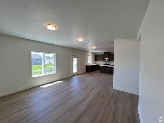 1154 E 1150 S, Garland, UT 84312 - unfurnished living room with dark wood finished floors, baseboards, and a textured ceiling
