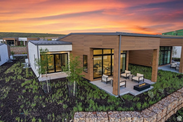 6312 Double Deer Loop, Park City, UT 84098 - back of property at dusk with an outdoor fire pit, a patio, metal roof, and a standing seam roof