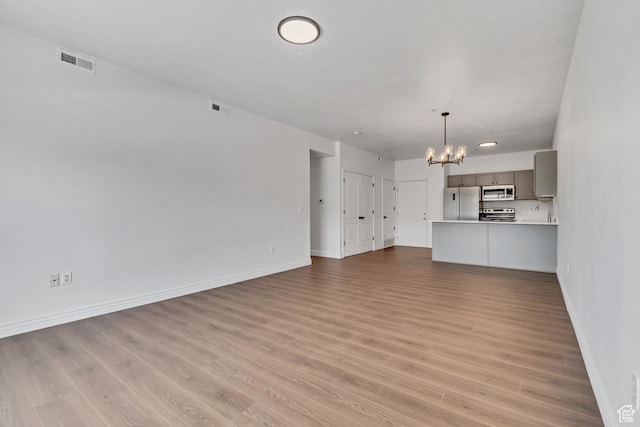 3478 S Cozy River Pl W Unit 210, West Valley City, UT 84119 - unfurnished living room featuring a chandelier, baseboards, and light wood-style flooring