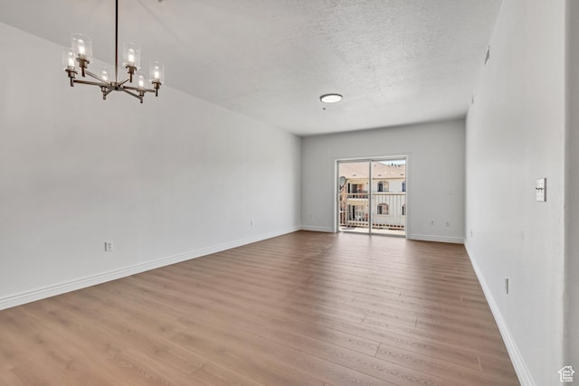 3478 S Cozy River Pl W Unit 210, West Valley City, UT 84119 - unfurnished room featuring wood finished floors, a chandelier, a textured ceiling, and baseboards