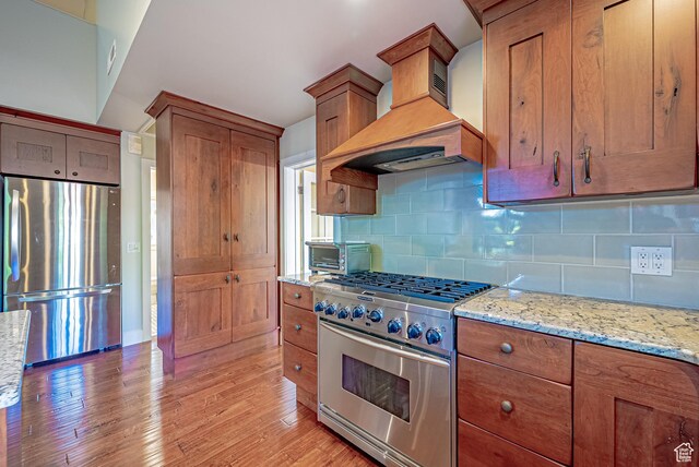 1820 E Redondo Ave S, Salt Lake City, UT 84108 - kitchen featuring stainless steel appliances, premium range hood, brown cabinetry, and light wood-type flooring