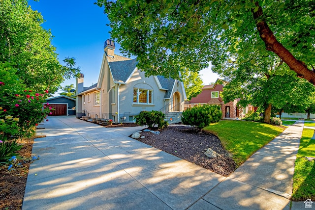 1820 E Redondo Ave S, Salt Lake City, UT 84108 - tudor home featuring stucco siding, a chimney, roof with shingles, a front lawn, and an outbuilding