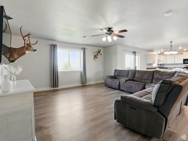 2699 N 3475 W, Plain City, UT 84404 - living area featuring a chandelier, a ceiling fan, baseboards, a textured ceiling, and light wood-style flooring
