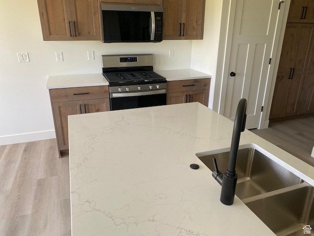 4618 W 75 N Unit 404, West Point, UT 84015 - kitchen with stainless steel gas range, a sink, baseboards, and light wood finished floors