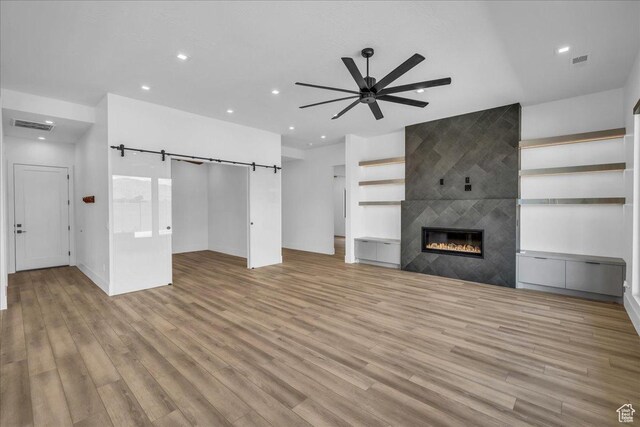 133 E Terrace Ln, Ivins, UT 84738 - unfurnished living room featuring ceiling fan, wood finished floors, recessed lighting, a tiled fireplace, and a barn door