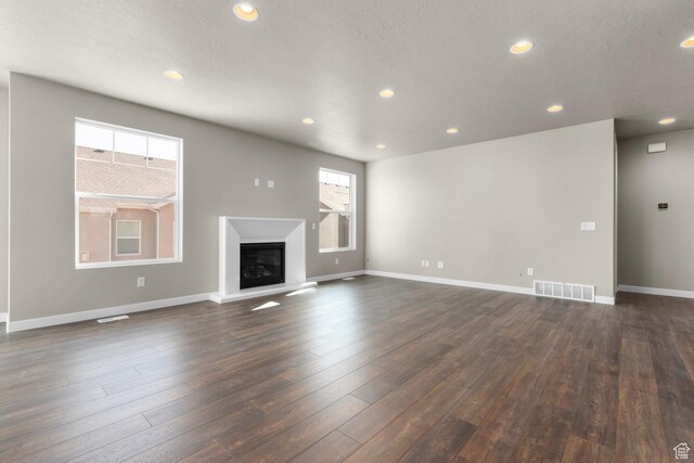 6564 N Bald Unit D195, Eagle Mountain, UT 84005 - unfurnished living room with a glass covered fireplace, recessed lighting, baseboards, and dark wood-style floors