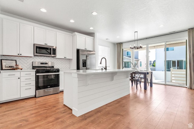 1797 N Avocet Dr, Salem, UT 84653 - kitchen with appliances with stainless steel finishes, a sink, tasteful backsplash, light wood-type flooring, and a chandelier