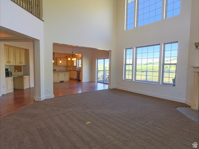 2307 Maple Leaf Dr, Cove, UT 84320 - unfurnished living room with dark colored carpet, a chandelier, a towering ceiling, and baseboards