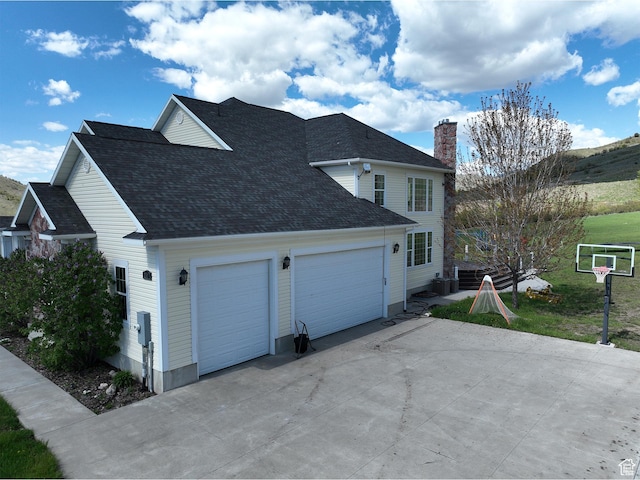 2307 Maple Leaf Dr, Cove, UT 84320 - view of home's exterior featuring driveway, a chimney, a garage, roof with shingles, and cooling unit