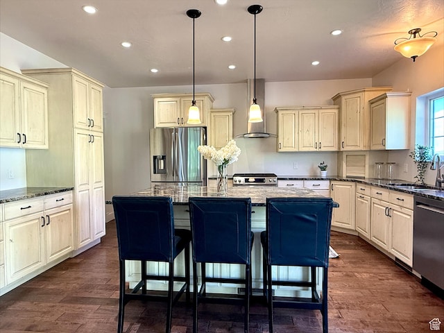 2307 Maple Leaf Dr, Cove, UT 84320 - kitchen with stainless steel appliances, cream cabinets, wall chimney exhaust hood, recessed lighting, and dark stone counters