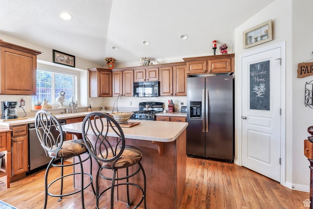 6329 W Basin Ridge Dr, West Valley City, UT 84128 - kitchen featuring stainless steel appliances, a center island, light countertops, brown cabinets, and light wood finished floors
