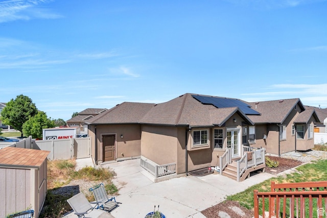 6329 W Basin Ridge Dr, West Valley City, UT 84128 - view of front facade featuring a patio, stucco siding, a deck, roof with shingles, and solar panels