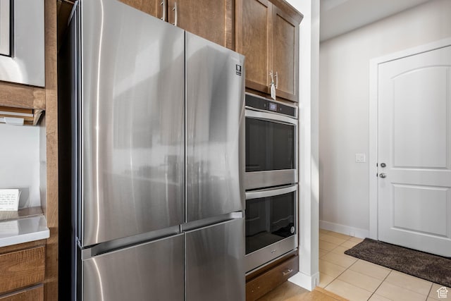 14908 S Fawley Ln, Herriman, UT 84096 - kitchen featuring appliances with stainless steel finishes, light tile patterned floors, brown cabinets, baseboards, and light countertops