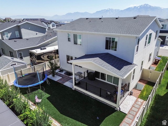 14908 S Fawley Ln, Herriman, UT 84096 - back of house with a mountain view, a trampoline, stucco siding, a shingled roof, and a patio