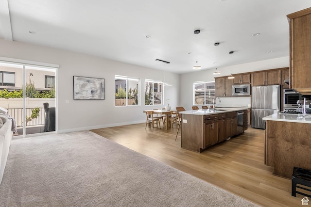 14908 S Fawley Ln, Herriman, UT 84096 - kitchen featuring appliances with stainless steel finishes, open floor plan, light countertops, an island with sink, and light wood finished floors