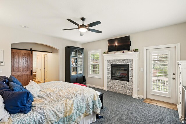 2271 W Crestview Cir, Cedar City, UT 84720 - carpeted bedroom with a barn door, a glass covered fireplace, baseboards, access to exterior, and ceiling fan