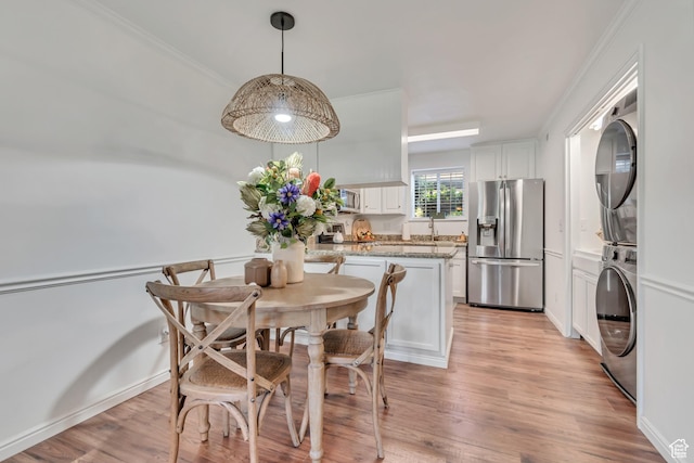 1030 S Orem Blvd Unit 23, Orem, UT 84058 - dining space with stacked washer and clothes dryer, light wood-style flooring, and crown molding
