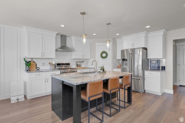 12473 S Desert Mesa Dr, Herriman, UT 84096 - kitchen featuring wall chimney exhaust hood, appliances with stainless steel finishes, a sink, backsplash, and a kitchen breakfast bar