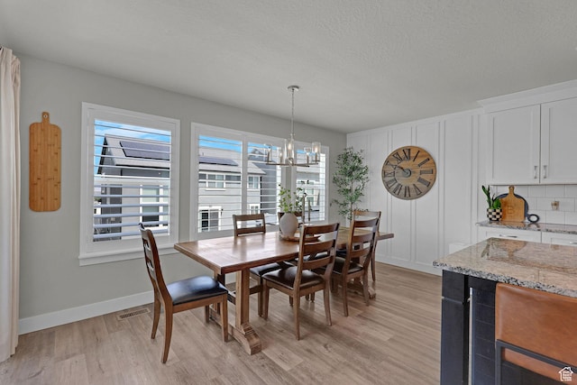 12473 S Desert Mesa Dr, Herriman, UT 84096 - dining room featuring light wood finished floors, a chandelier, baseboards, and a textured ceiling