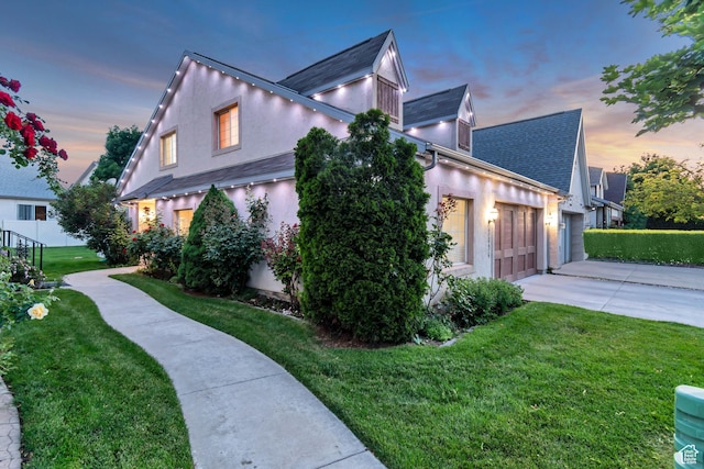 3094 E Somerset Dr, Spanish Fork, UT 84660 - property exterior at dusk featuring concrete driveway, stucco siding, a lawn, a garage, and a shingled roof