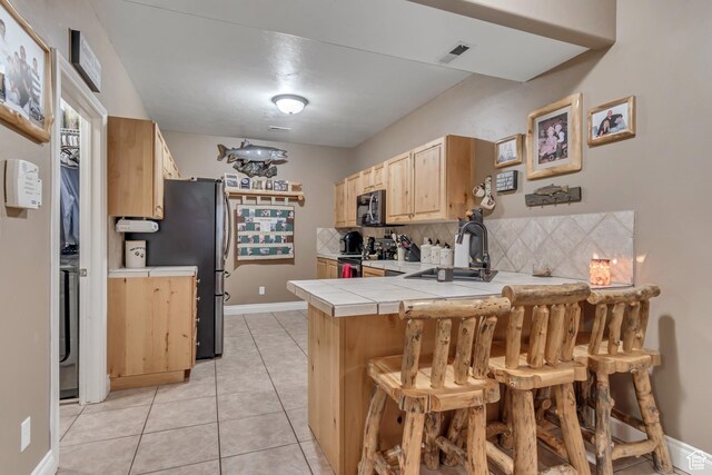 3094 E Somerset Dr, Spanish Fork, UT 84660 - kitchen with electric stove, tile counters, light brown cabinets, a peninsula, and backsplash