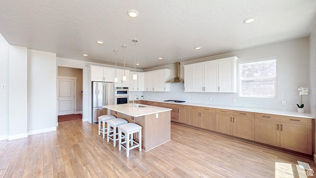 833 N Union Bench Dr W Unit 62, Mapleton, UT 84664 - kitchen with stainless steel appliances, a sink, a breakfast bar, wall chimney range hood, and light countertops
