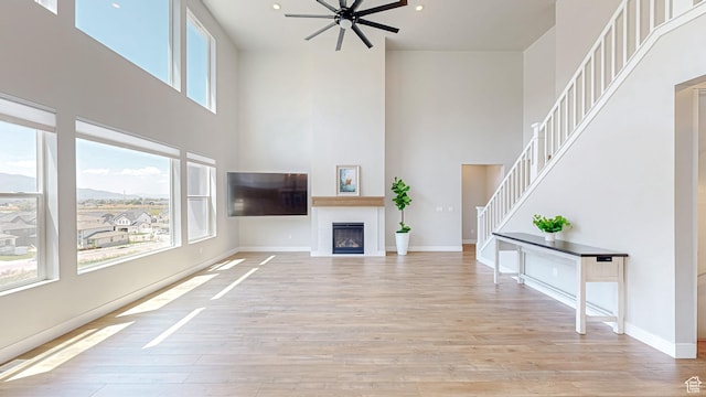 833 N Union Bench Dr W Unit 62, Mapleton, UT 84664 - unfurnished living room featuring a towering ceiling, ceiling fan, light wood-style floors, stairs, and a fireplace