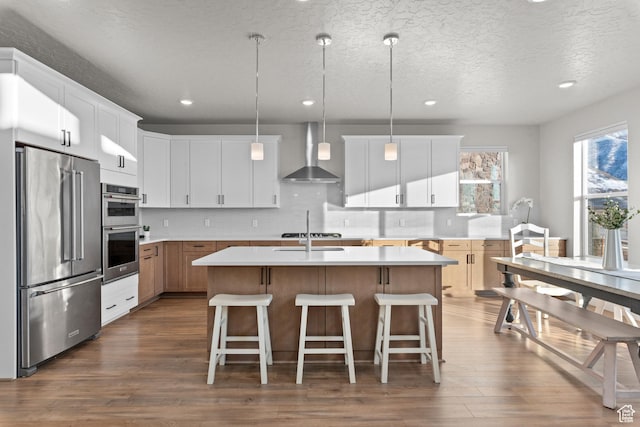 833 N Union Bench Dr W Unit 62, Mapleton, UT 84664 - kitchen featuring stainless steel appliances, wall chimney exhaust hood, dark wood finished floors, light countertops, and a kitchen island with sink