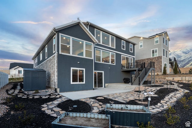833 N Union Bench Dr W Unit 62, Mapleton, UT 84664 - back of house at dusk with stone siding, a patio, stairway, and stucco siding